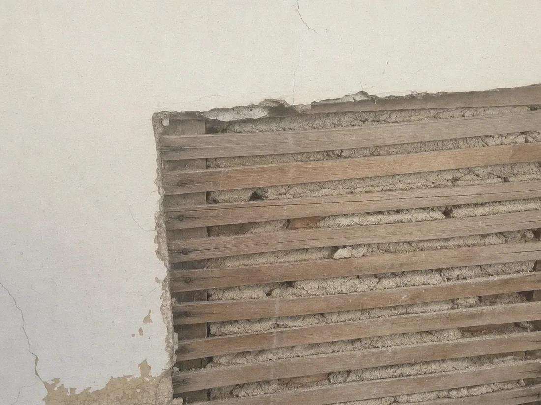 Plaster cut back to a firm edge exposing wood lath and the plaster keys behind it