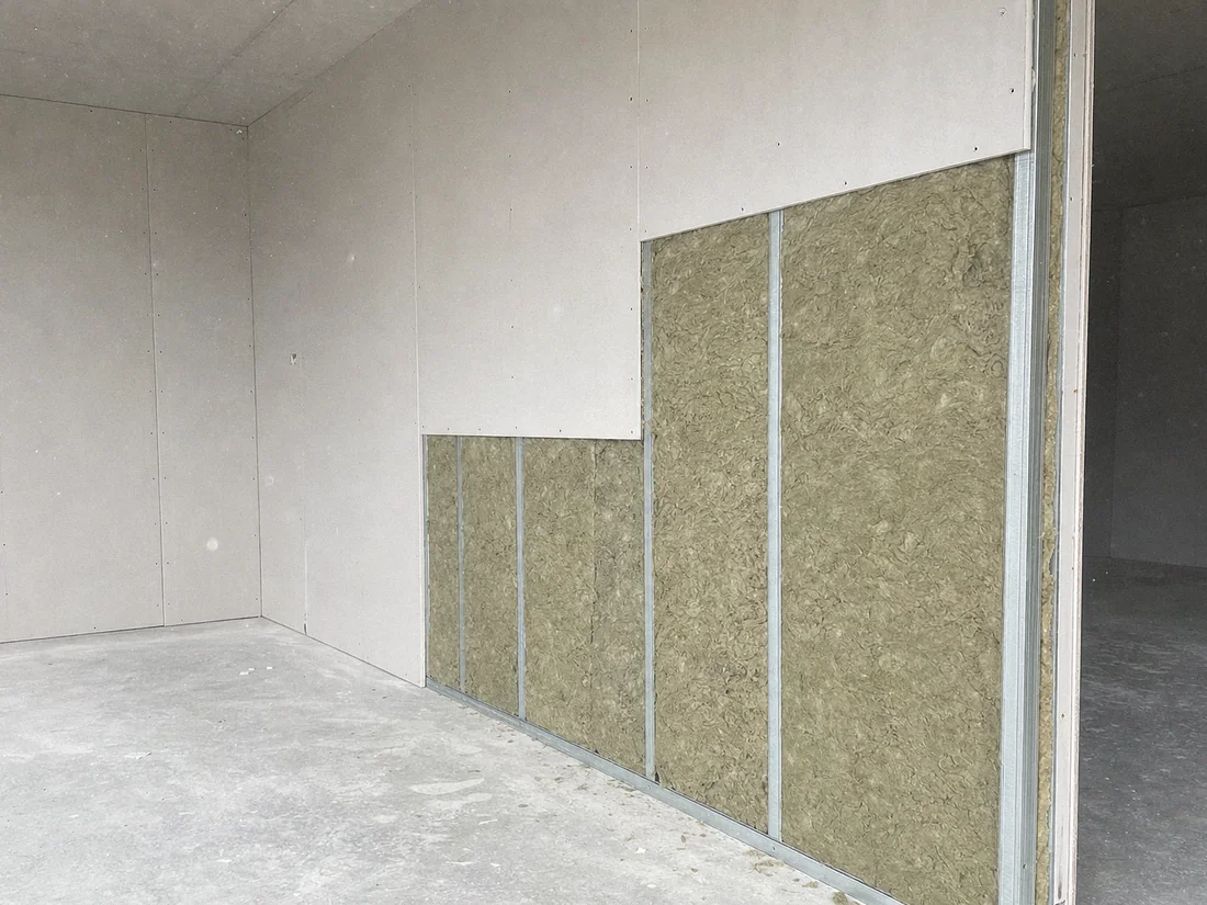 Partition wall part-boarded showing mineral wool packed into the stud cavities behind