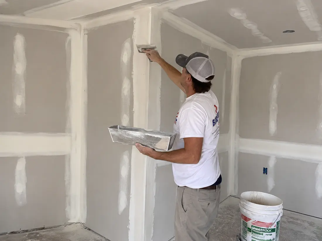 Drywall tape being bedded into joint compound